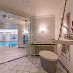 Indoorpoolbereich mit Glaswand, Sitzbank und Wanddekoration.