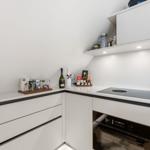 Moderne Küche mit weißen Schränken, Induktionskochfeld und integriertem Ofen.