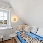 Schlafzimmer mit Dachschräge, Fenster, Bett und Schreibtisch.