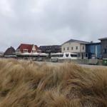 Strandpromenade mit Hotels und Dünenvegetation im Hintergrund.