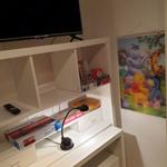 Schreibtisch mit Fernseher, Spielzeug und Kinderposter an der Wand.