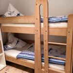Holz-Etagenbett mit Matratzen und Bettwäsche mit Segelbootmotiv.