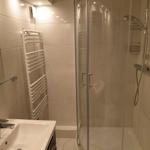 Badezimmer mit Dusche, Waschbecken und Heizkörper