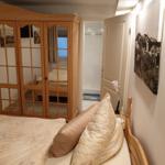 Schlafzimmer mit Holzbett, Spiegelschrank und Badzugang