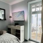 Zweites Schlafzimmer mit Flachbildfernseher und direktem Zugang zum West-Teakholzbalkon mit Strandkorb und hochwertigen Sitzmöbeln.