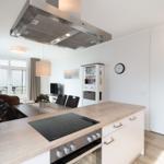 Küche mit Holzoberfläche und Induktionskochfeld. Essbereich und Wohnzimmer im Hintergrund.
