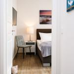 Schlafzimmer mit Bett, Nachttisch, Stuhl und Wandbild