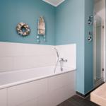 Badezimmer mit Badewanne, Dusche und Waschbecken. Wandfarbe türkis, dekorative Wandobjekte.
