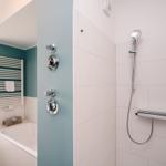 Dusche mit Duschbrause und Whirlpoolbad mit Heizkörper