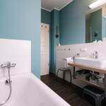 Badezimmer mit Badewanne, Duschkopf, Waschbecken und Spiegel