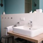 Badezimmer mit Waschbecken auf Holzkonsole, Spiegel und weißen Fliesen.