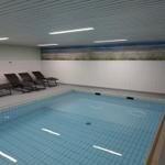 Innere Schwimmhalle mit Liegestühlen und Strandbildwand