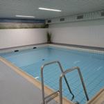 Innere Schwimmhalle mit Pool und Strandbild an der Wand.