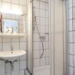 Badezimmer mit Dusche, Waschbecken und Spiegel.