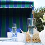 Tisch mit Gläsern, Tassen und Blumen vor Strandkorb