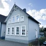 Ein zweistöckiges Haus mit grauer Fassade und weißen Fensterrahmen unter blauem Himmel.