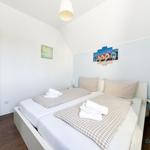 Schlafzimmer mit Doppelbett, Kissen und Bettwäsche. Wandbild und Nachttisch.