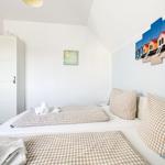 Schlafzimmer mit Doppelbett, Kleiderschrank und Wandbild von Strandhütten.