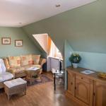 Living room with seating, cabinet, and window under sloped ceiling.