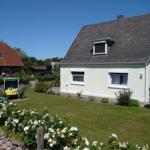 House with garden, flower beds, and terrace under blue sky.