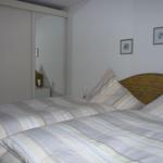 Two beds with striped bedding, sliding wardrobe, and two pictures on the wall.