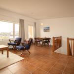 Living and dining area with wooden table, chairs, and view of the terrace.