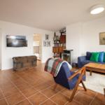 Living room with sofa, TV, and wooden furniture.