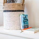 A basket and books are on a white surface.
