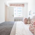Bedroom with bed, window, and decorative pillows.
