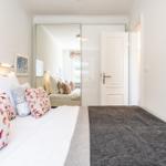 Bedroom with bed, pillows, and mirrored closet. Door leads to a hallway.