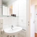 Bathroom with sink, mirror, and heater. Toilet area is adjacent.