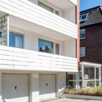 Modern apartment with balcony and garage area in urban surroundings.