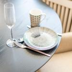 Round table with plate, fork, coffee cup, and champagne glass.