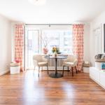 Living room with dining table, two chairs, TV, and windows with curtains.
