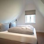 Schlafzimmer mit Dachschräge, Bett, Fenster und Nachttisch.