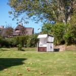 Haus mit Strohdach, Garten mit Liegestuhl und Bäumen.