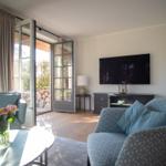 Wohnzimmer mit zwei Sesseln, Fernseher und Terrassentür.