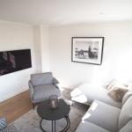 Wohnzimmer mit Sofa, Sessel, Couchtisch und Wandbild.