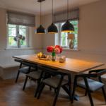 Esszimmer mit Holztisch, Sitzbänken und drei Hängelampen.