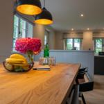 Holztisch mit Obst, Blumen und Lampen im Essbereich.