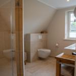 Badezimmer mit Dusche, Toilette und Waschtisch unter Dachschräge