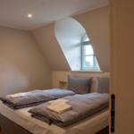 Schlafzimmer mit Doppelbett und schräger Wand. Fenster mit Bogenform.
