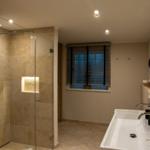 Bad mit Dusche, Waschbecken und Fenster mit Jalousie
