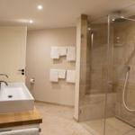 Badezimmer mit Dusche, Waschbecken und Handtüchern.