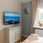 Schlafzimmer mit Fernseher, Fenster und Bett