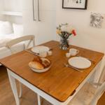 Holztisch mit Frühstück und Bett im Hintergrund.