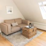 Ein Wohnzimmer mit Sofa, Korbtablett und Dachfenster.