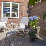 Terrasse mit zwei Liegestühlen, Tisch und Blumen in Körben.