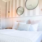 Schlafzimmer mit Bett, zwei runden Spiegeln und einer Leiter an der Wand.