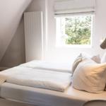 Schlafzimmer mit Dachschrägen, Bett, Fenster und Stuhl.